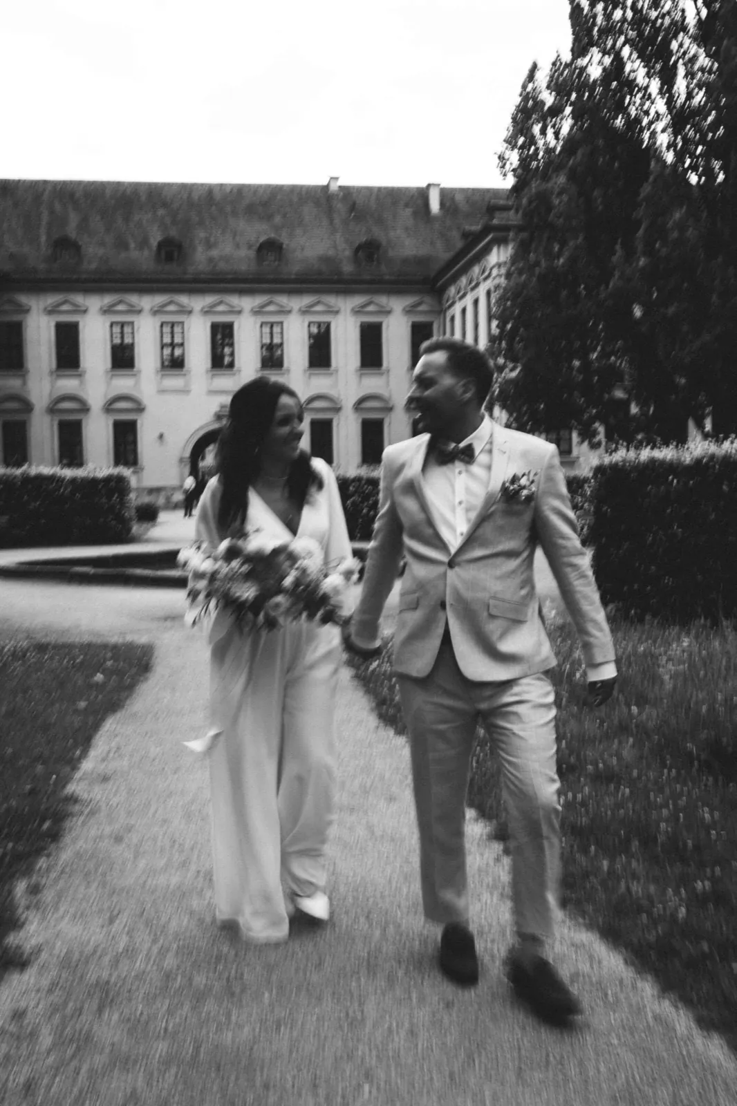 Amelie & Andi – Hand in Hand lachend vor einem historischen Gebäude