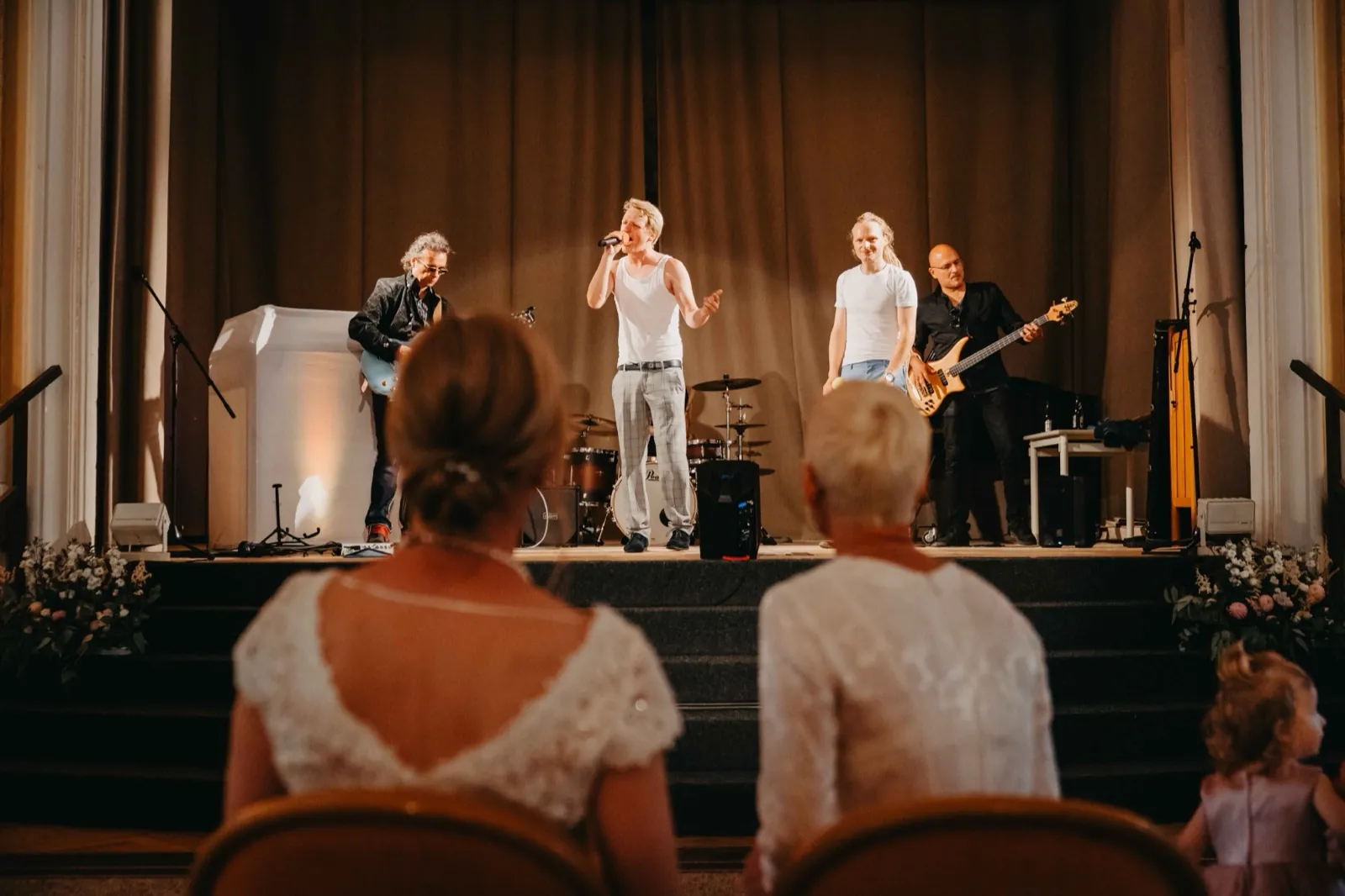 Barbara & Gabi – Eine Band spielt auf einer Bühne vor sitzenden Gästen bei einer Hochzeitsfeier