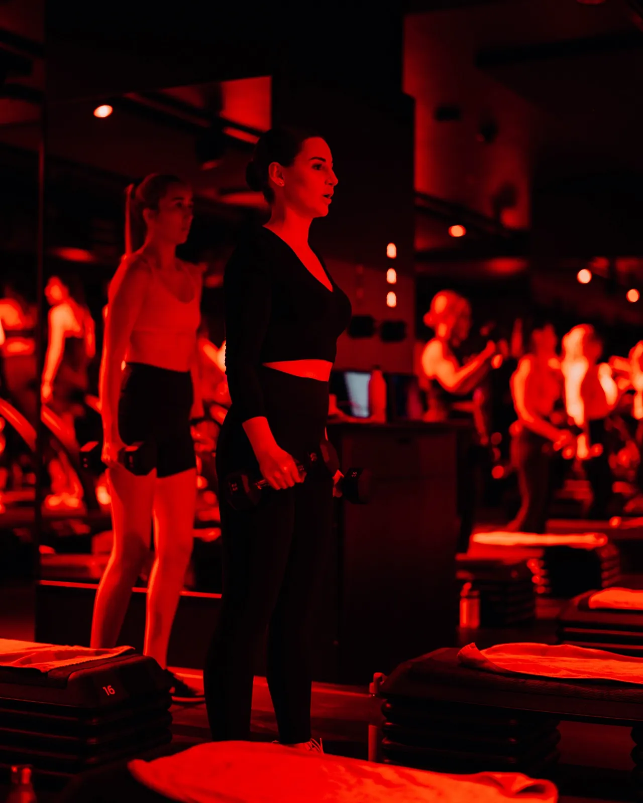 Barry's Frankfurt – Zwei Frauen trainieren mit Hanteln in einem Fitnessstudio mit roter Beleuchtung
