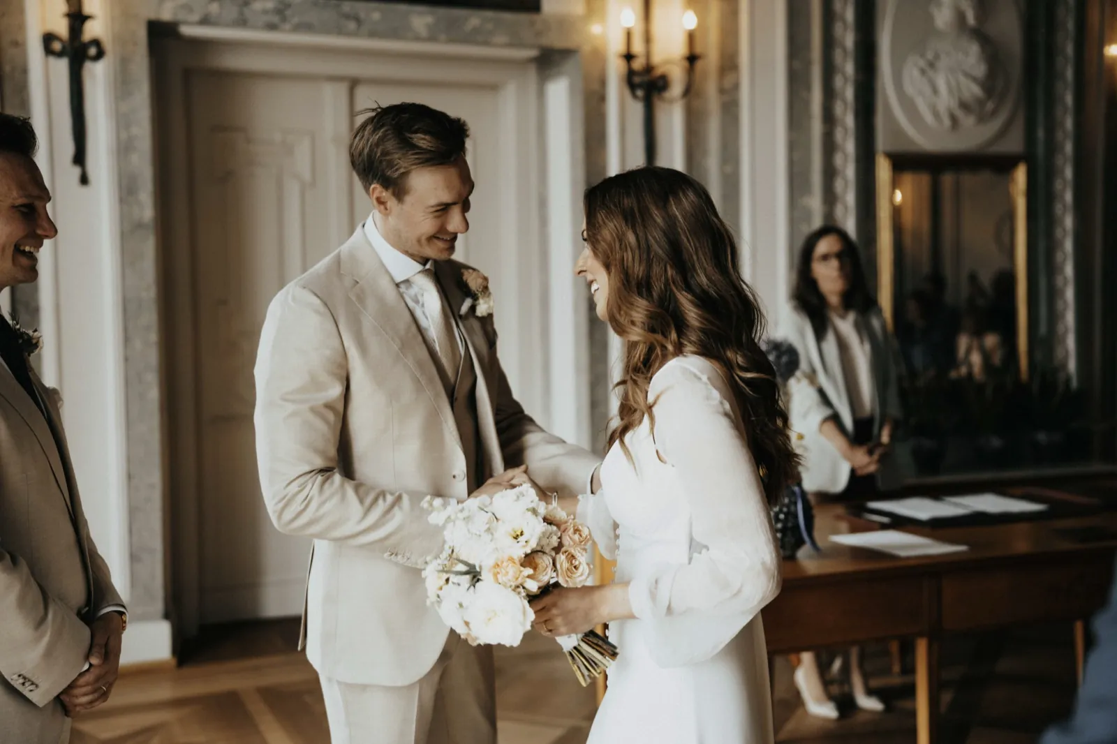 Deana & Sebastian – Ein Brautpaar lächelt sich während der standesamtlichen Trauung im Innenraum an