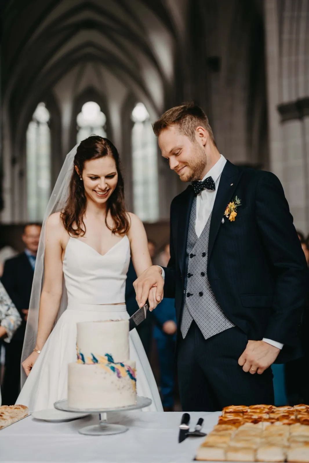 Isa & Nico – Ein Brautpaar schneidet gemeinsam die Hochzeitstorte in einer Kirche an