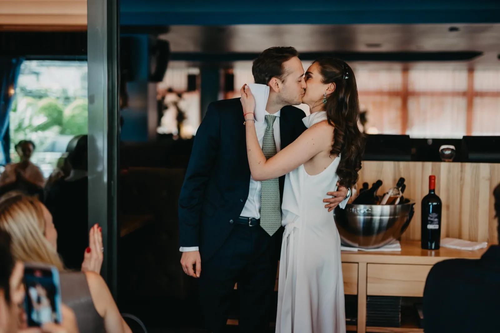 Jessica & Adrian – Ein Brautpaar küsst sich innig während der Hochzeitsfeier im Innenraum