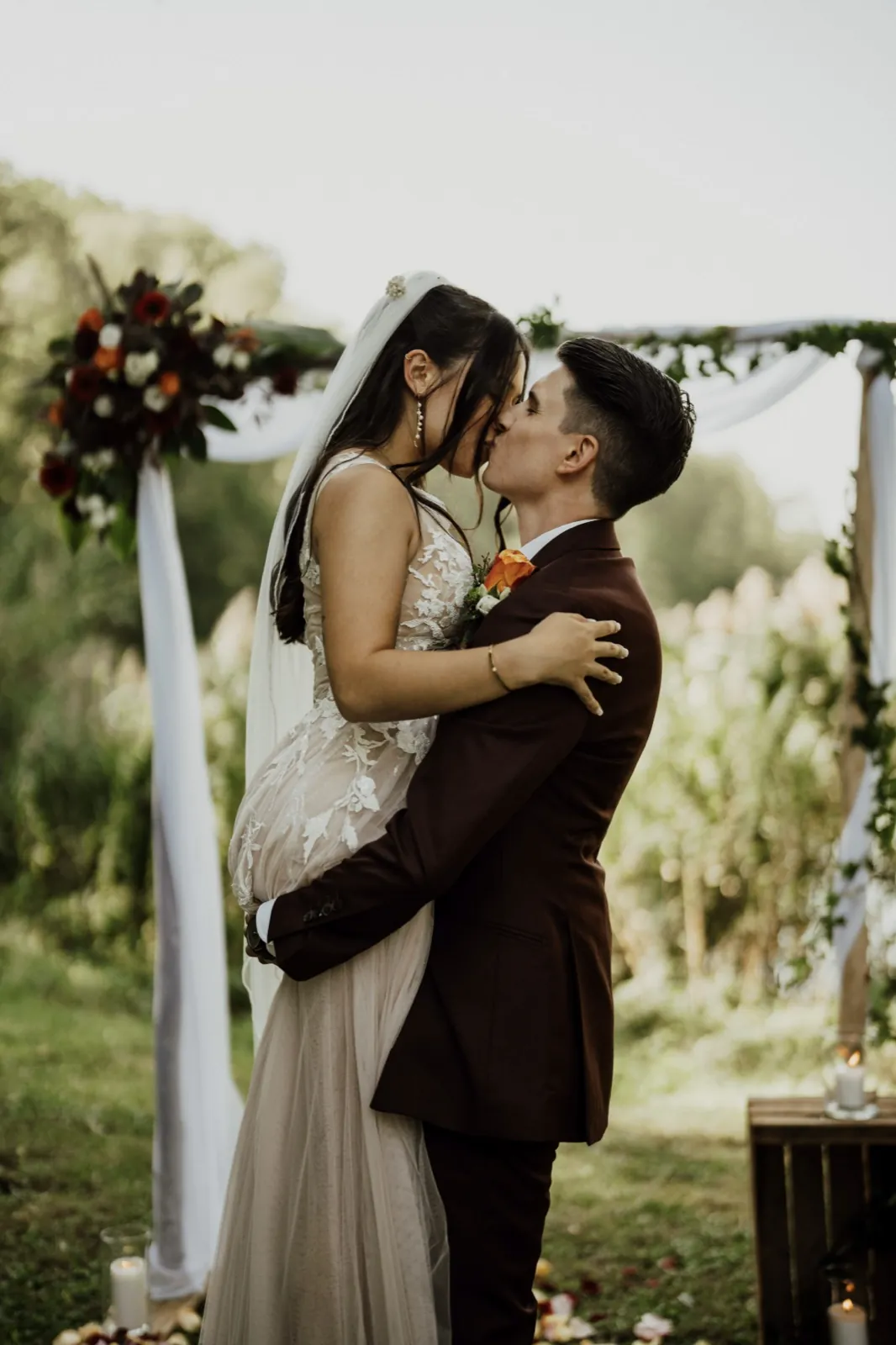 Marie & Thomas – Ein Bräutigam hebt seine Braut hoch und küsst sie vor einem Hochzeitsbogen