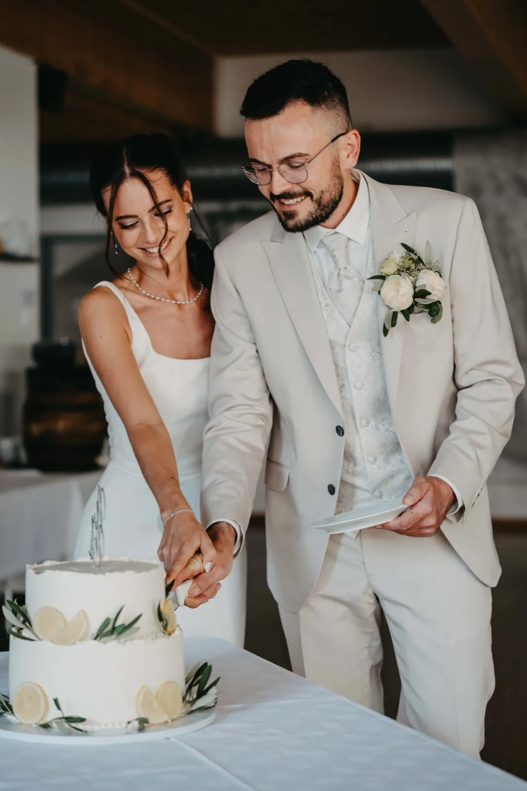 Michelle & Felix – Ein Brautpaar schneidet gemeinsam lächelnd die weiße Hochzeitstorte an