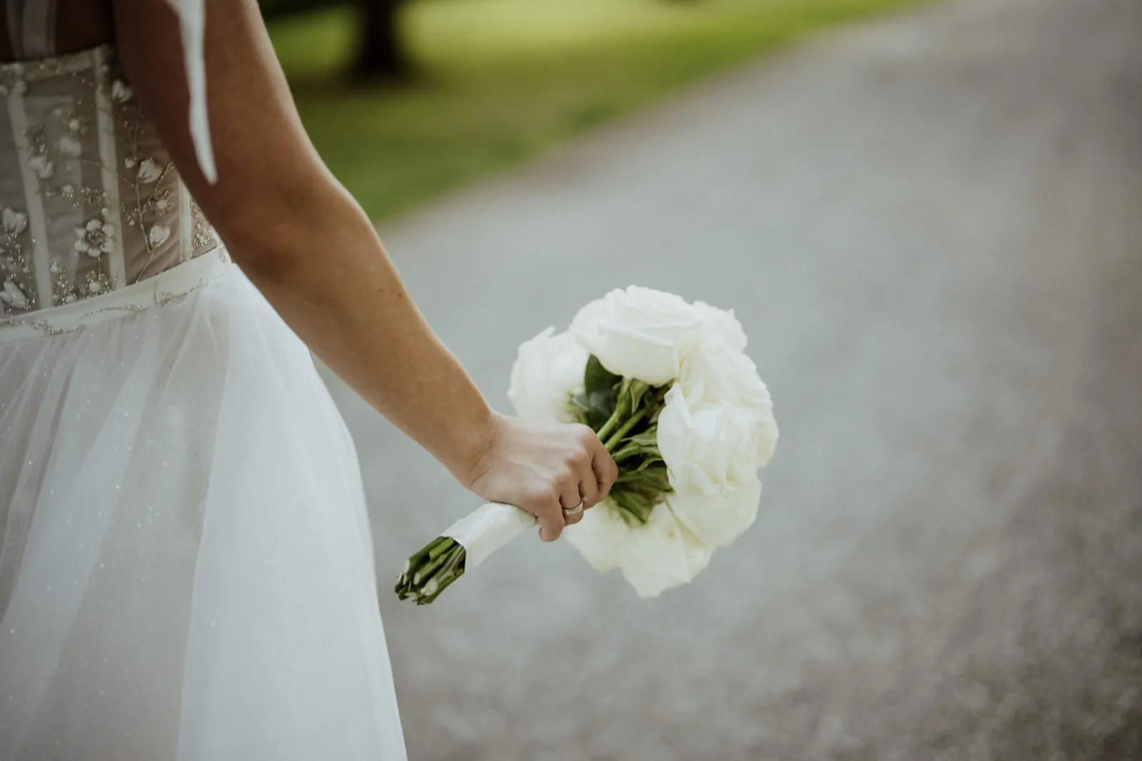 Nadine & Raphael – Eine Braut hält einen Strauß weißer Rosen in der Hand