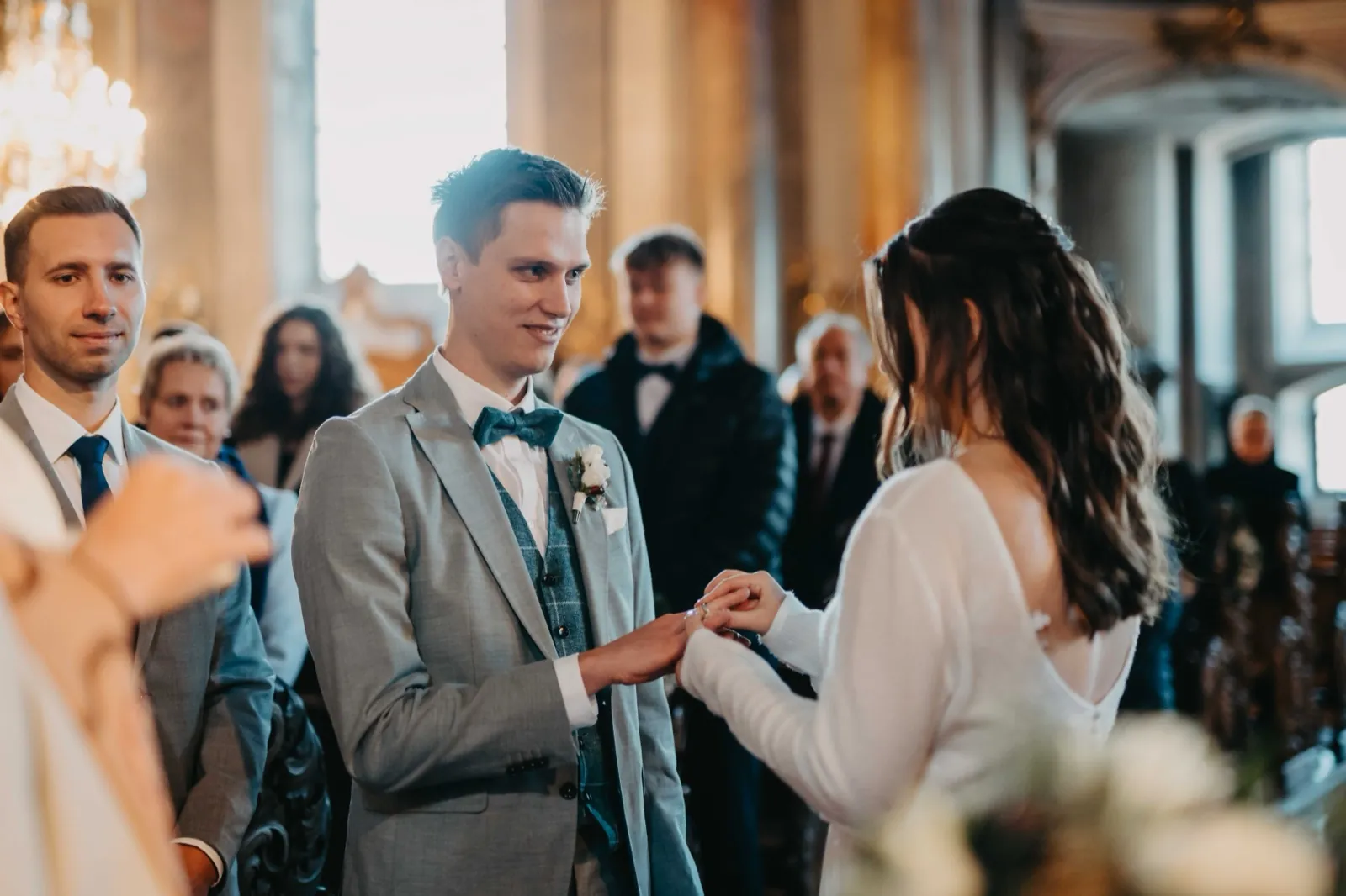 Sophie & Mirko – Ringtausch bei der Trauung: die Braut steckt dem lächelnden Bräutigam den Ring an